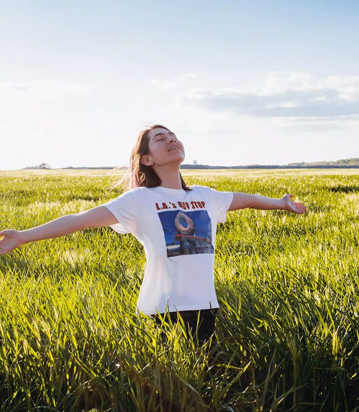 Image d'une jeune femme qui tend les bras vers le ciel dans un champs